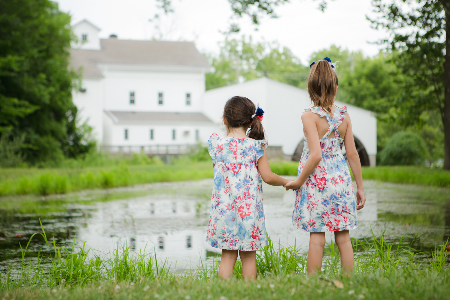 Siblings holding hands in front of a pond